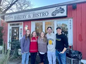 A group of college students gather for a photo in front of Upcountry Provisions: Bakery and Bistro.