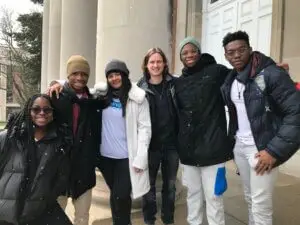 Students pose for picture on concrete steps with snowflakes falling