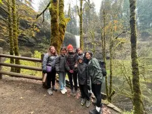 Group of students pose in front of wooded area with waterfall