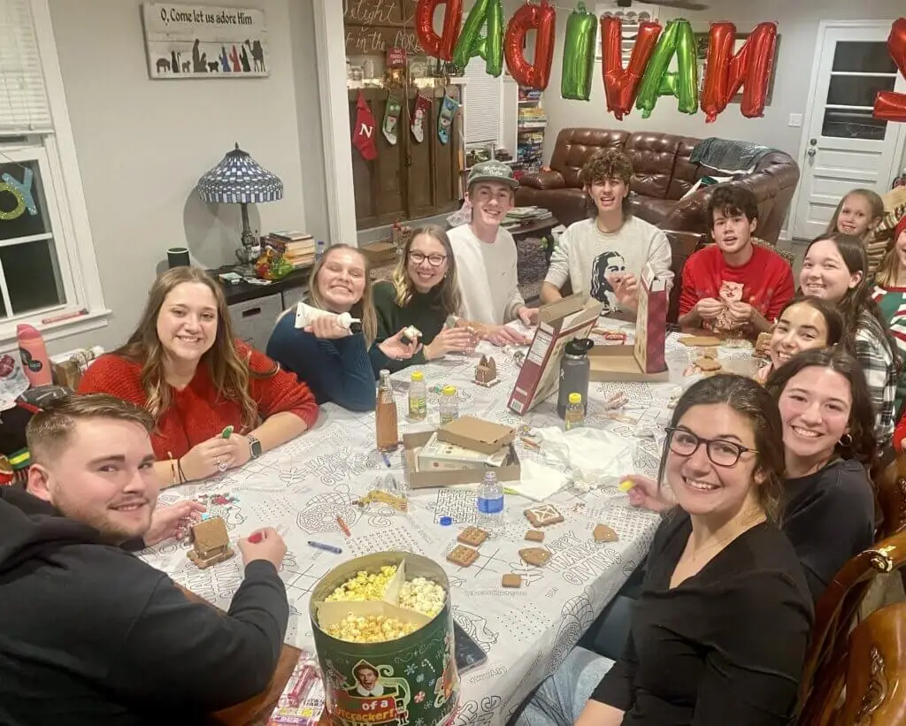 College students gathered around a table building gingerbread houses