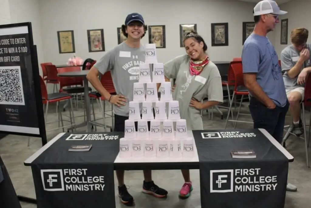 College students pose behind stacked cup pyramid