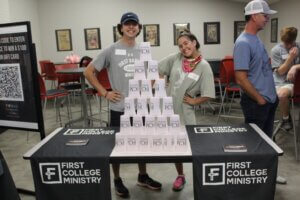 College students pose behind stacked cup pyramid