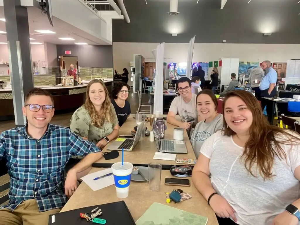 College students meet together with laptops and notebooks on table