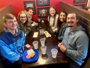 Six college students sit in booth together at pizza restaurant