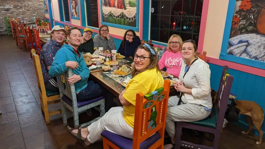 Group of college students sit at colorful Mexican restaurant for dinner with fellow church members