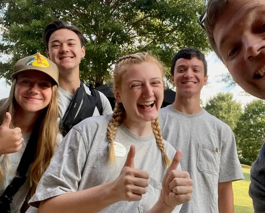 College students pose together with thumbs up