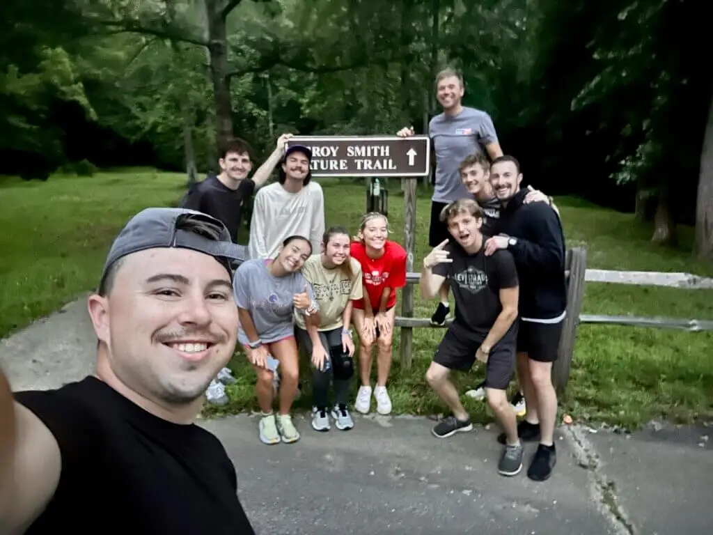 College students pose for selfie with trail sign outside