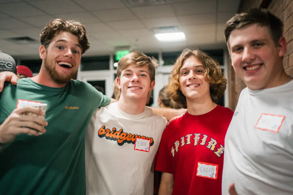 Four guys pose for a picture with arms around each other's shoulders