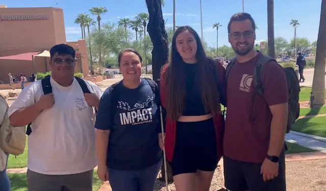 Four college students pose for picture outside