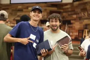 Two college guys pose for picture holding their bibles in their left hands