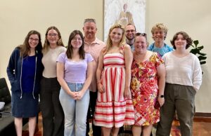 A group of young men and women pose for a picture inside