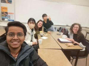 International students pose for a selfie while seated in a classroom.