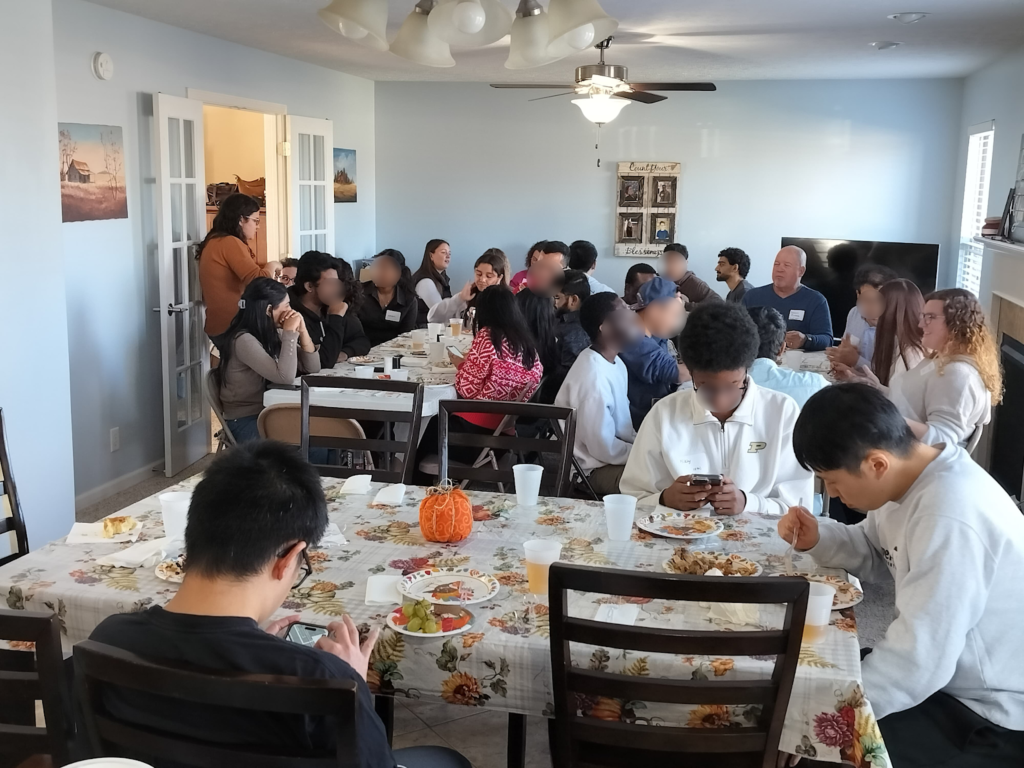 Multiple tables filled with American and international students for Thanksgiving.