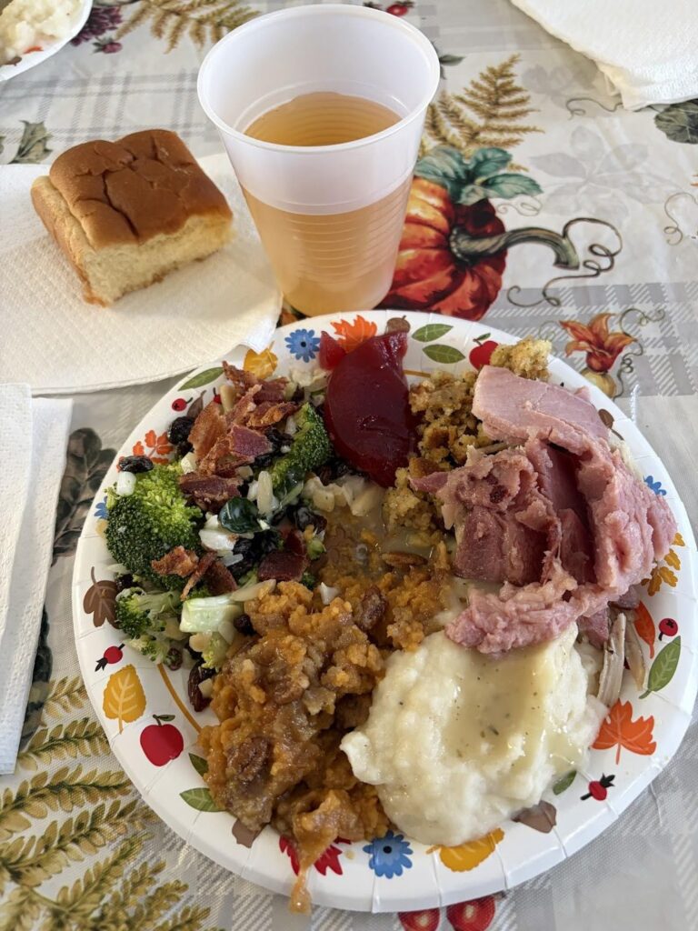 International Student Ministry: Thankful for God Moving! 1 Plate filled with Thanksgiving food sitting on a Thanksgiving table cloth beside a plastic cup of tea.
